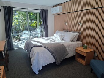 A bedroom with a bed, a window, and a wall-mounted air conditioning unit.