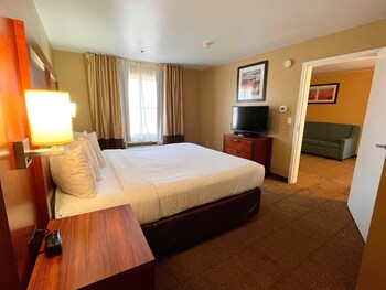 A hotel room with two beds, a television, a desk, and a chair.