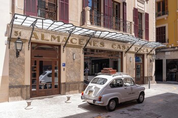 A vintage car parked in front of a building with a sign reading 'CASA ROCA'.