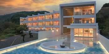 A modern hotel with multiple floors, a swimming pool, and a mountain backdrop.