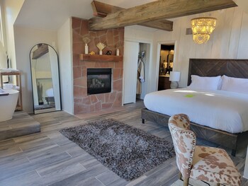 Enjoy a warm and inviting space with a large mirror, sink, and comfortable bed.