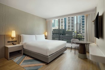 Relax in a stylish space with a large bed, flat-screen TV, and a small table for work or relaxation.