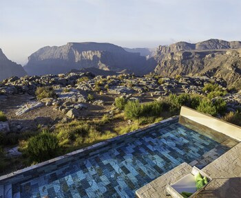 A resort with a central pool, multiple lounge areas, and a mountainous backdrop.