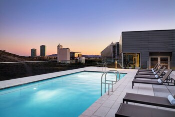 Una piscina al aire libre, sombrillas, sillones reclinables de piscina