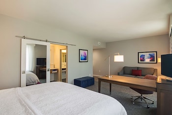 A modern hotel lobby with a dining area, seating, and a TV.