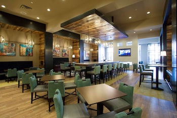 A modern restaurant with wooden accents, a bar area, and multiple seating options.