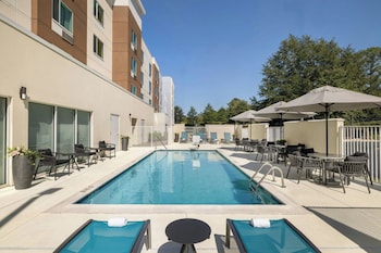 Un hotel moderno con un letrero llamativo que dice "Towneplace Suites by Marriott". Cuenta con una entrada espaciosa con área cubierta y asientos al aire libre.