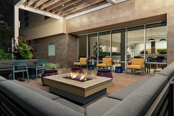 An outdoor patio with a fire pit, seating, and a view of the building's interior.