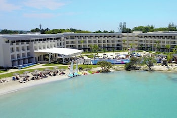 A resort with multiple buildings, a beach area with sun loungers, and a view of the sea.