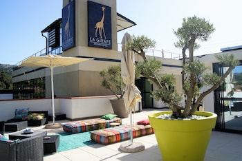 A rooftop terrace with outdoor seating, a large potted tree, and a view of distant mountains.