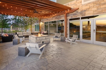 An outdoor patio with stone flooring, a fire pit, and various seating arrangements.
