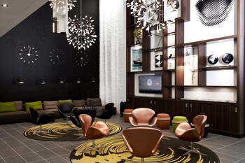 Una sala moderna con un sofá seccional, varios sillones, un televisor e iluminación decorativa.