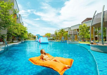 Un espace piscine extérieur moderne, doté d’une terrasse en bois, de chaises longues et d’un parasol jaune.