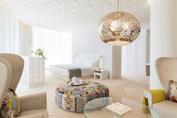 Un espace piscine intérieur luxueux, doté d’un plafond au design géométrique, d’un sol à carreaux et de chaises longues.