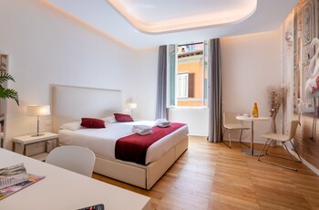A modern bedroom with a bed, a desk with a laptop, and a large window with curtains.
