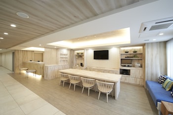 A modern kitchen with a long dining table, built-in cabinets, and a flat-screen TV.