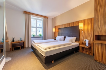 Relax in a serene space with a neatly made bed, wooden desk, and large mirror.