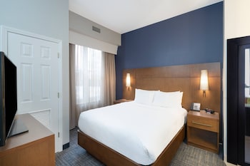 A modern hotel room with a living area, kitchenette, and a fireplace.