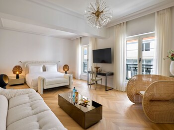 Un salon moderne comprenant un canapé, des fauteuils, une table basse, une plante en pot et une étagère ornée d’objets décoratifs.