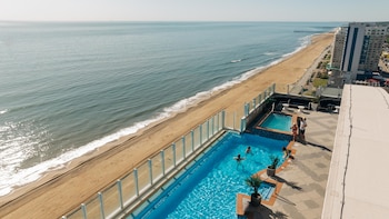 Una piscina infinita con vista al océano al atardecer.
