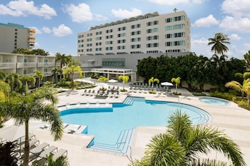 A resort pool area with multiple sun loungers, a small pool, and a view of the ocean.