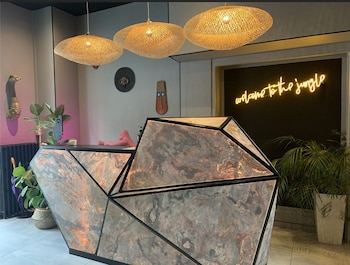 Ein Restaurant mit modernem Interieur, das eine Mischung aus Holz- und Polstermöbeln, ein großes Wandgemälde an der Rückwand und eine Decke mit eingelassener Beleuchtung bietet.