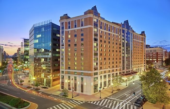 A hotel with a modern glass facade, a flag, and a sign indicating it is a Marriott hotel.