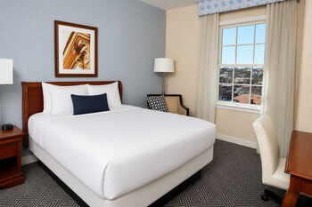 A spacious lobby with multiple seating areas, a grand piano, and a reception desk.
