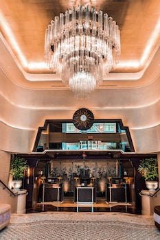 Un vestíbulo con una lámpara de candelabro grande, un reloj y una mesa de recepción.