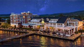 Un hotel frente al agua con varias construcciones, zonas de estar al aire libre y un muelle.