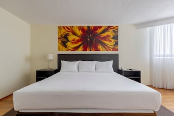 Una recepción de hotel moderna con techo de vidrio, un mostrador de recepción y una pantalla digital.