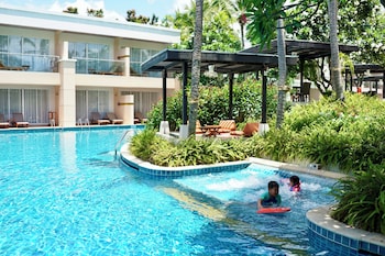 A resort with a central pool, palm trees, and a view of the ocean.