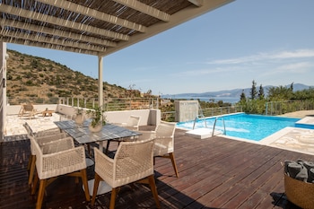 A poolside area with lounge chairs, a table, and a view of the sea.