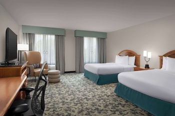 Entrada de hotel con un camino cubierto, palos de señales y una fachada bien iluminada.