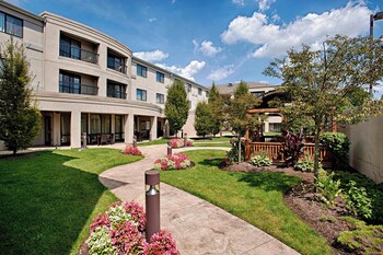 Relax in the shaded patio area, surrounded by lush plants and comfortable seating for dining or socializing.
