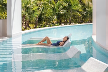 A resort with a swimming pool, beach, and ocean view.