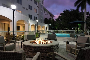 A poolside area with outdoor seating, a fire pit, and a building with multiple balconies.