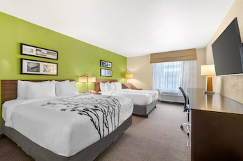 A hotel room with a bed, a sofa, a coffee table, and wall art.