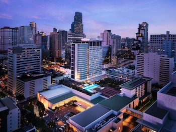 A high-rise hotel with a prominent 'Pullman' sign, surrounded by other tall buildings.