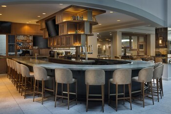 A multi-level hotel lobby with a central atrium, multiple dining areas, and a pool.
