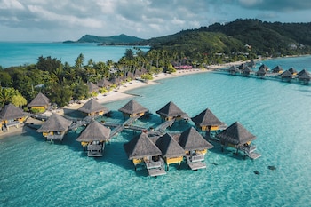 An overwater bungalows arrangement with a beach and palm trees.