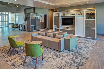 A Holiday Inn & Suites building with a modern design, featuring a prominent entrance and a parking area with handicapped accessibility.