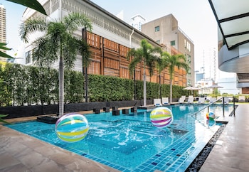 Una piscina al aire libre, sombrillas, sillones reclinables de piscina