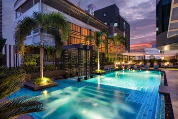 Una piscina al aire libre, sombrillas, sillones reclinables de piscina
