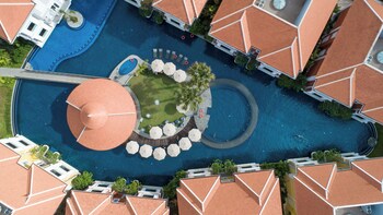 Un bâtiment à deux étages doté d’une piscine, entouré d’une végétation luxuriante et de palmiers.
