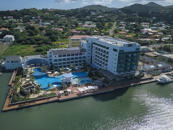 A resort pool area with a clear view of the sea, lounge chairs, and a covered seating area.