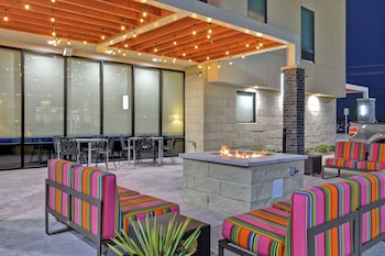 An outdoor patio with a fire pit, seating with colorful cushions, and string lights.
