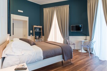 Une chambre d’hôtel moderne équipée d’un lit, d’une table de chevet et d’un coin café avec une machine à café, des tasses et un plateau.