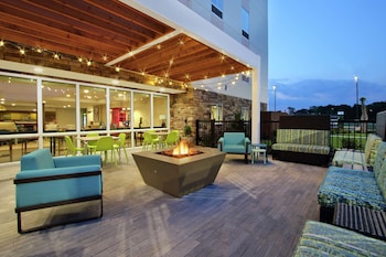 Un patio al aire libre con un brasero, asientos e iluminación colgante.