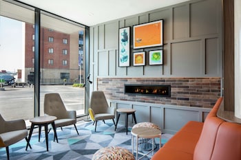 A modern dining area with high ceilings, large windows, and a mix of bar and table seating.